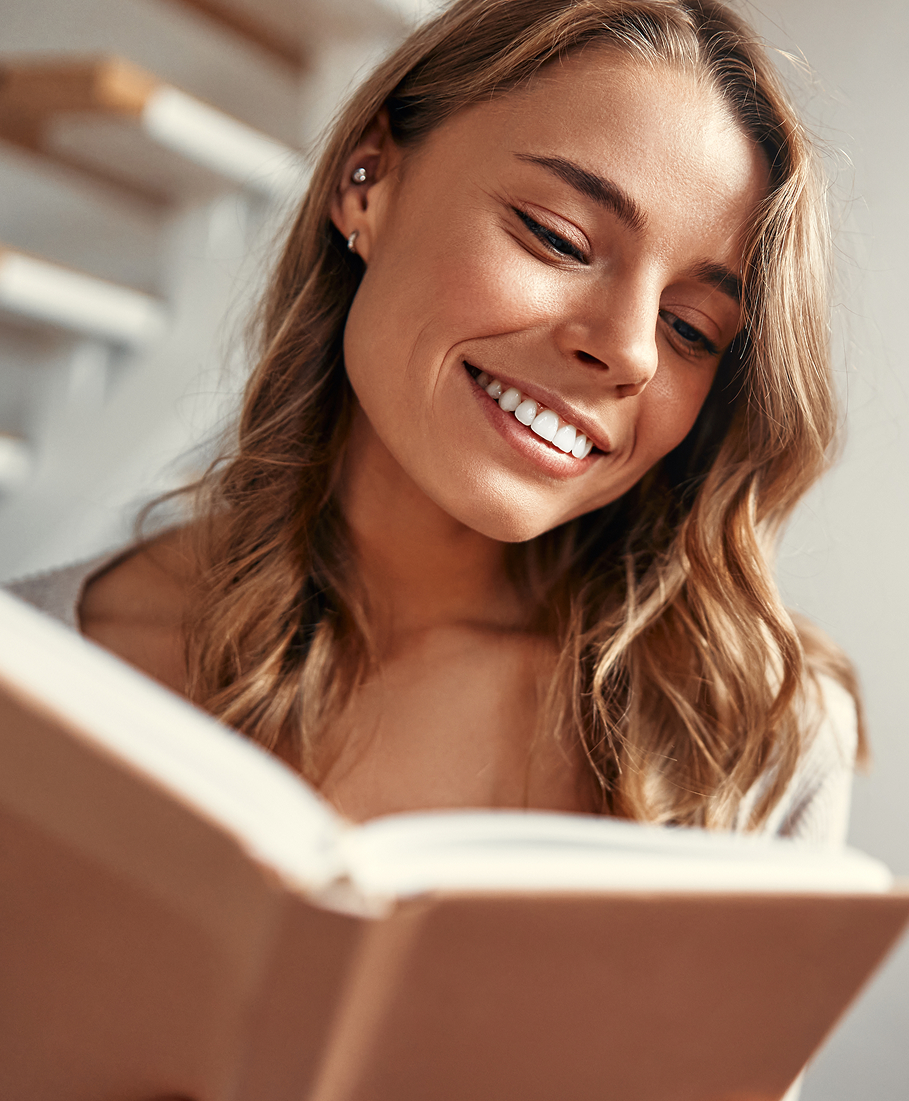 Woman with a smile reading a book indoors