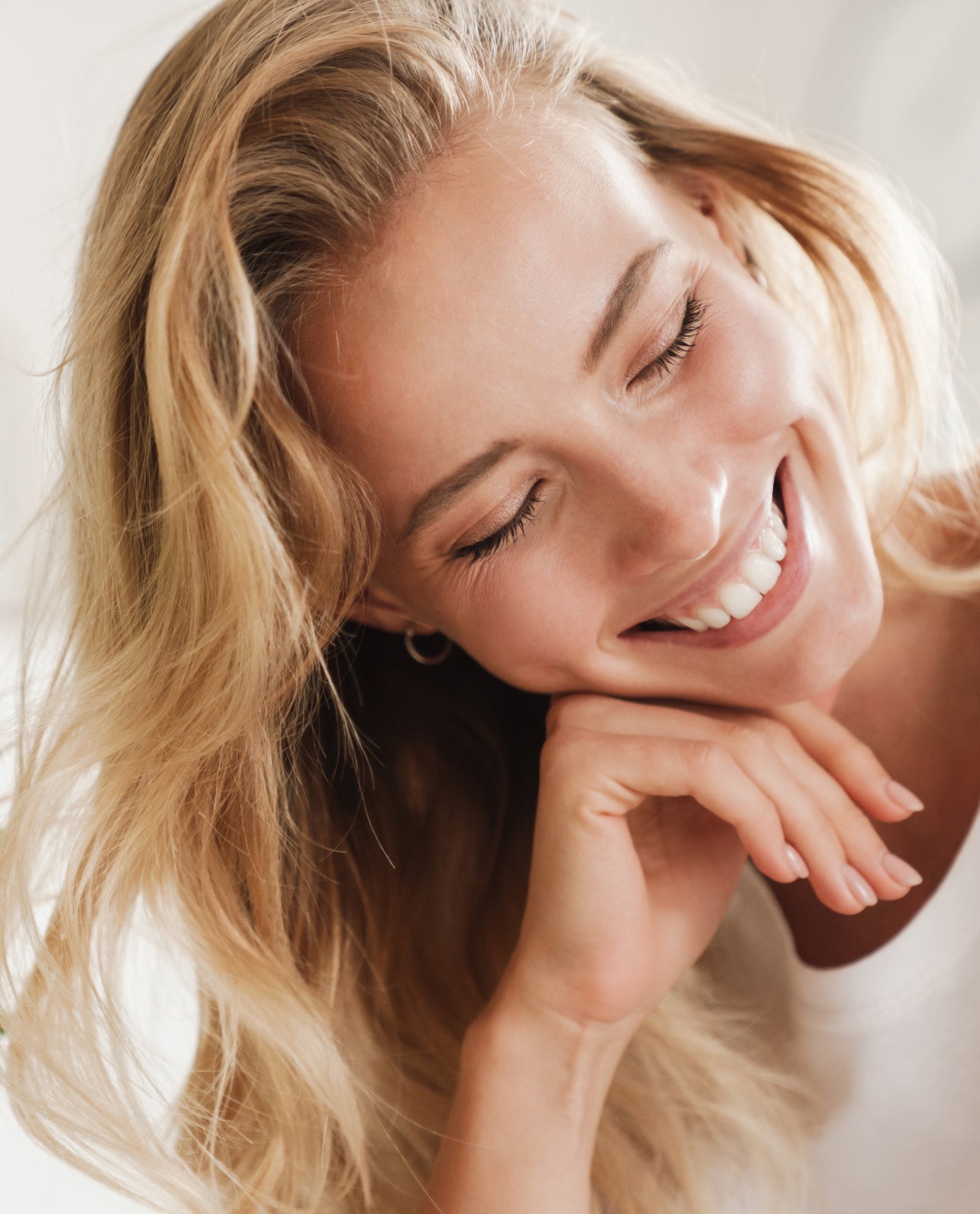 Woman with blonde hair smiling with a blurred background