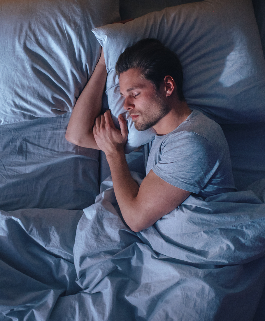 Man sleeping in bed with blue sheets and pillows