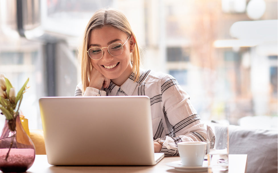 Woman using a laptop in a bright room with a blurred background