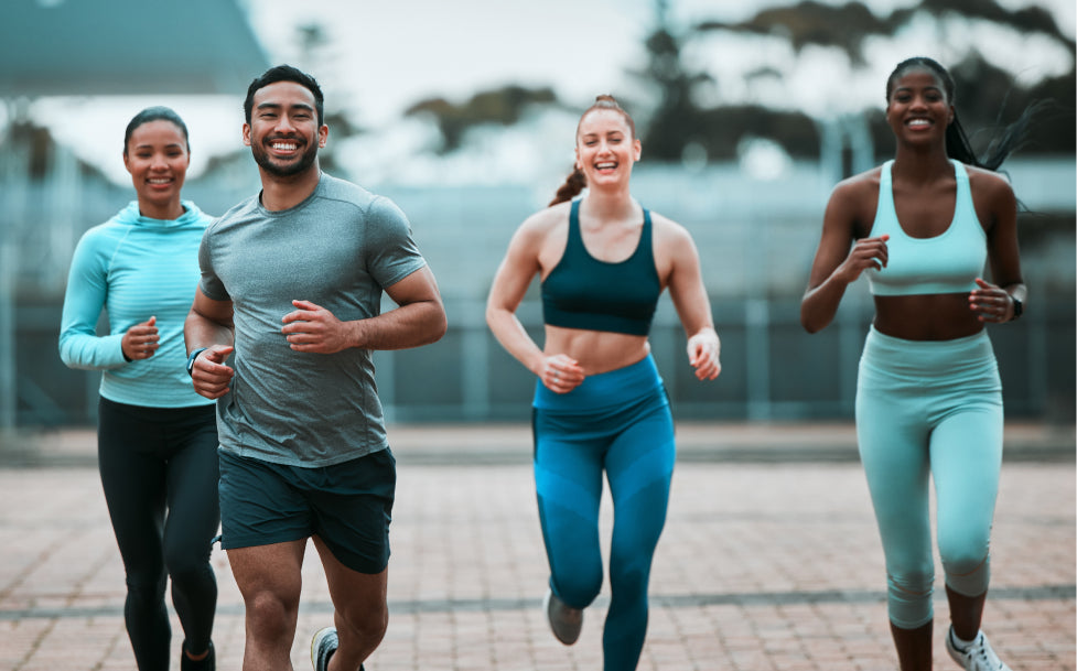 Group of four people running outdoors on a path with blurred background