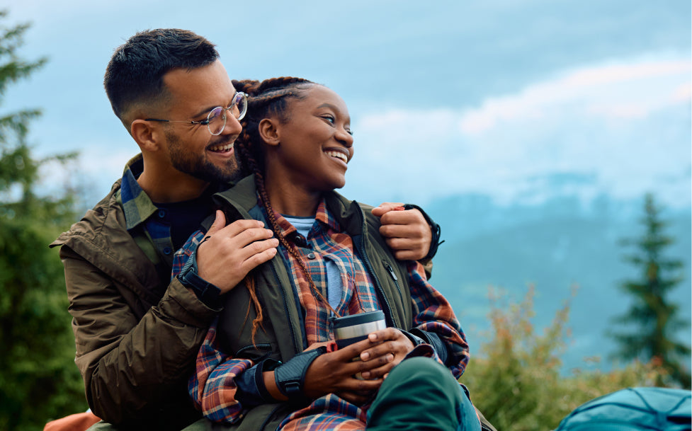 Man and woman hugging outdoors with mountains in the background