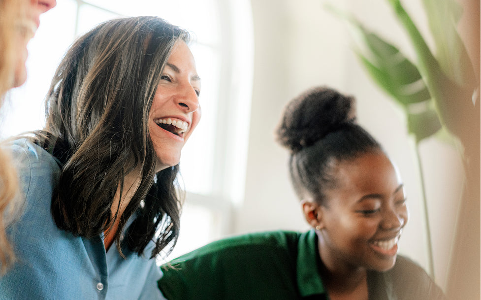 Two women laughing together in a bright indoor setting