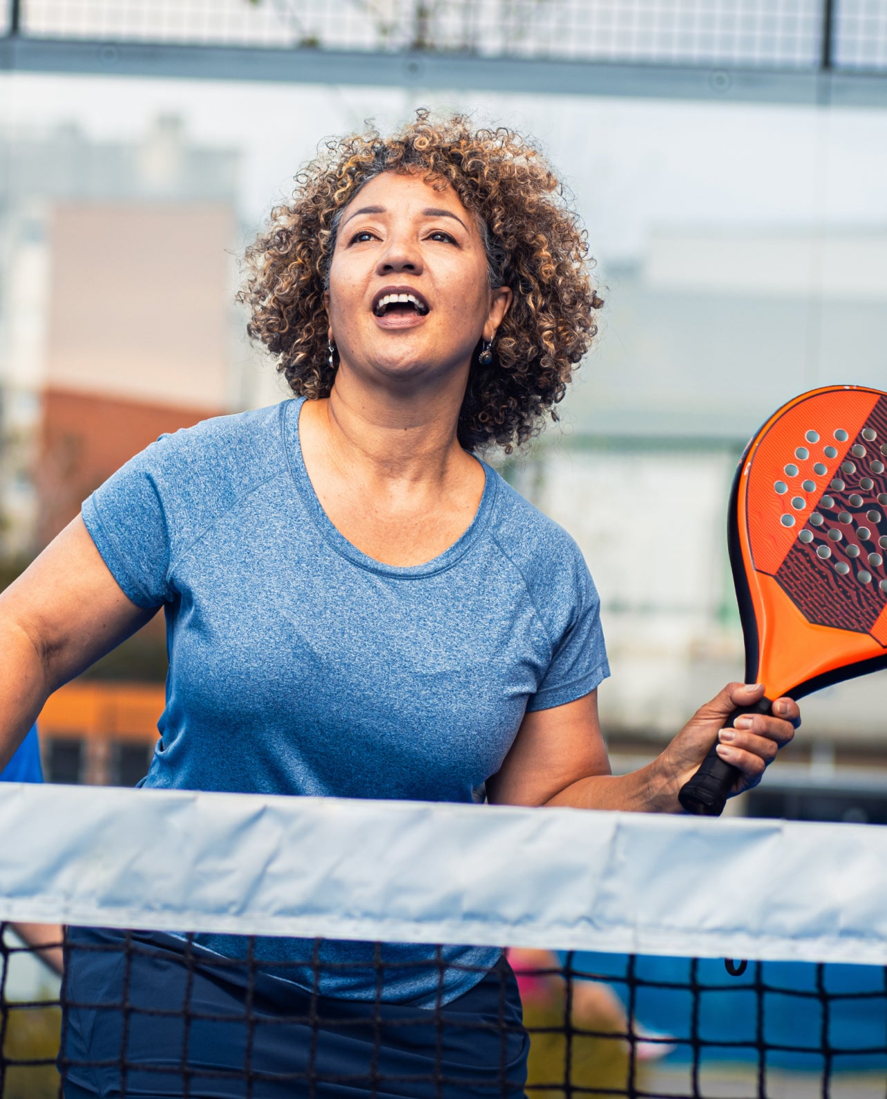 Woman playing paddleball holding a paddle on a court