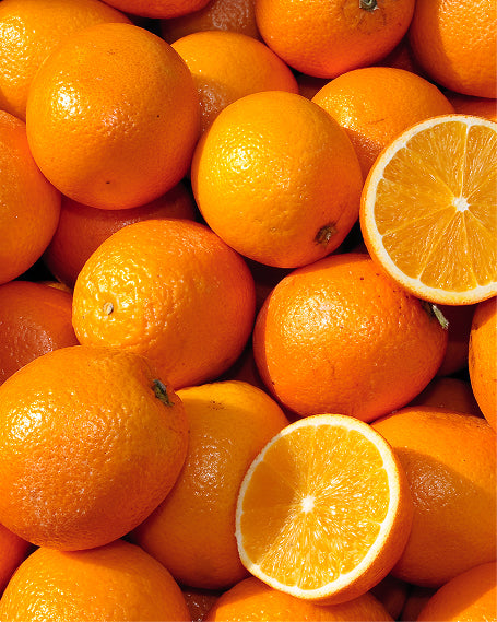 Close up of a pile of oranges with two halves on top.