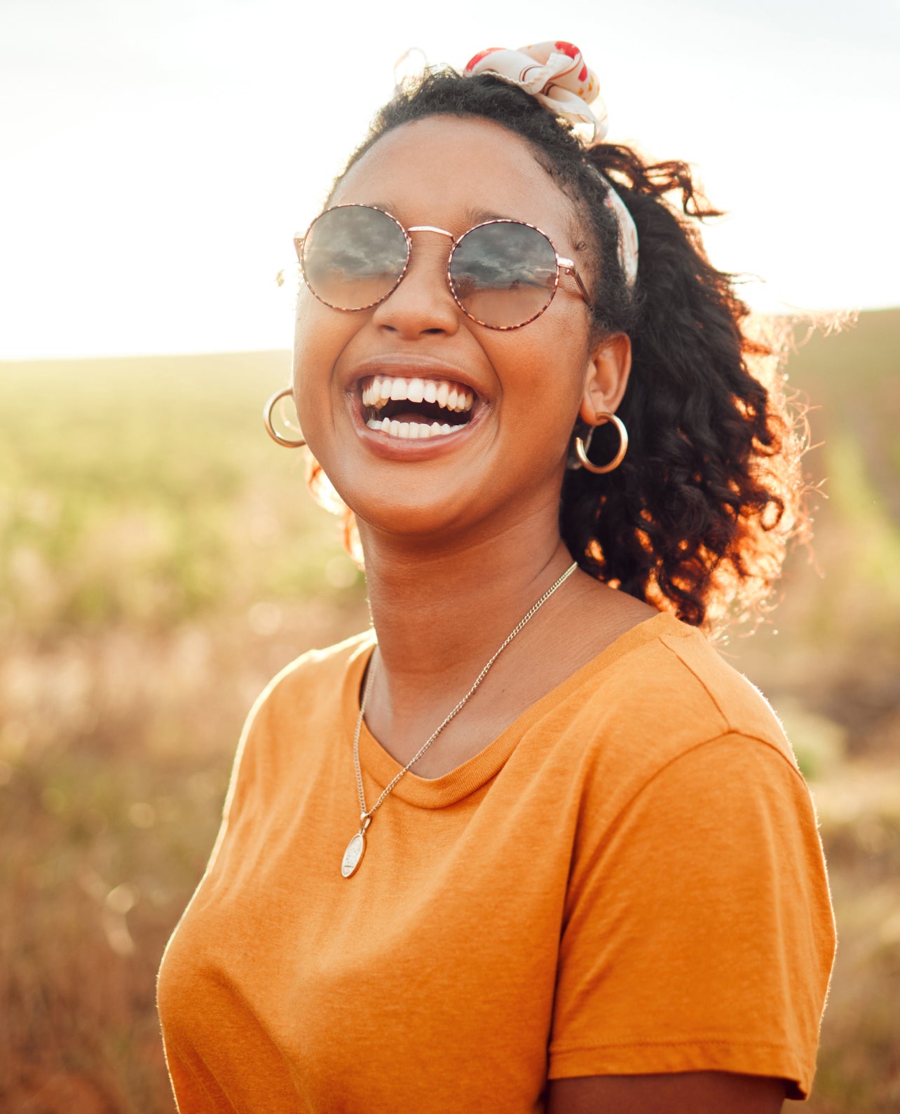 Woman wearing sunglasses and an orange shirt outdoors