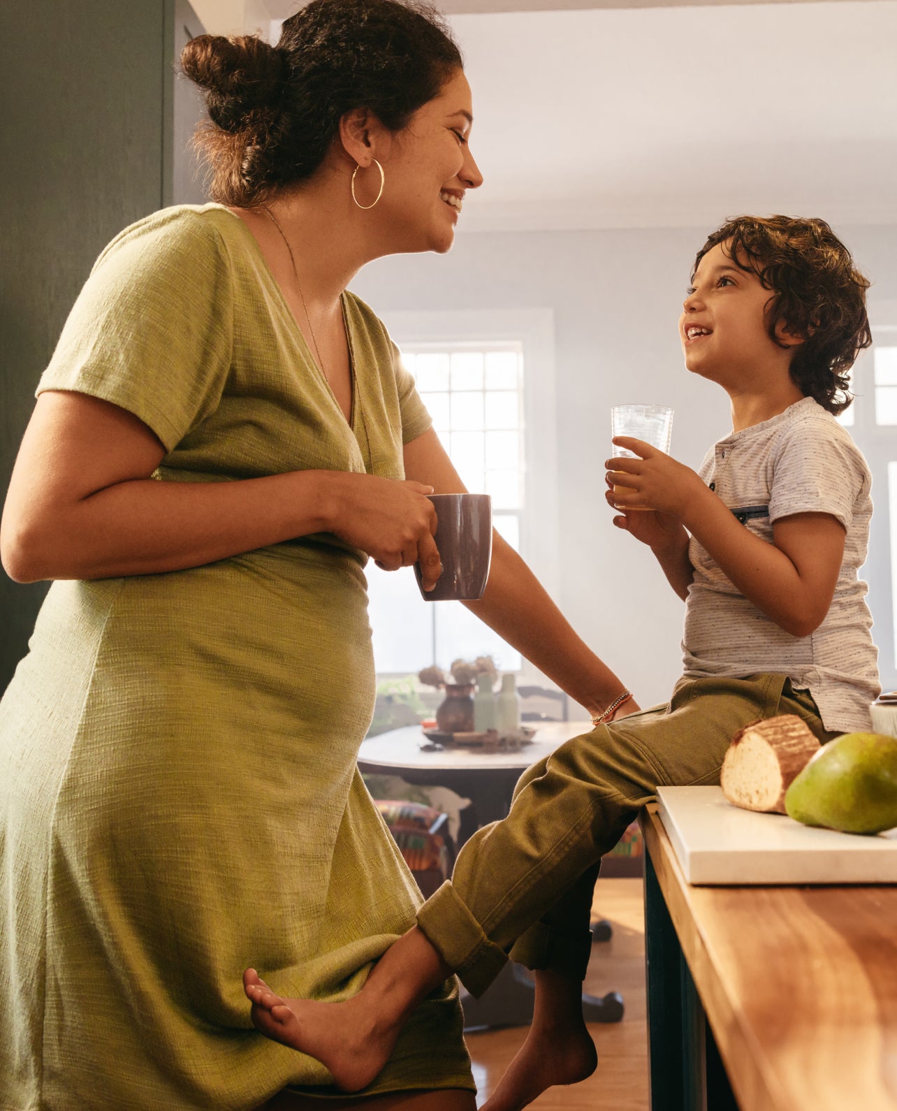 Woman and child in a kitchen, woman holding a mug, child holding a glass.