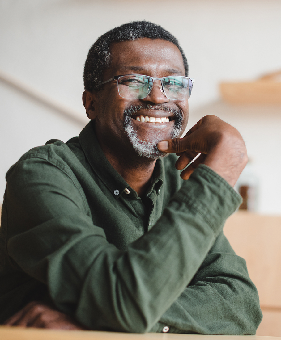 Man wearing glasses and a green shirt, smiling with a blurred background