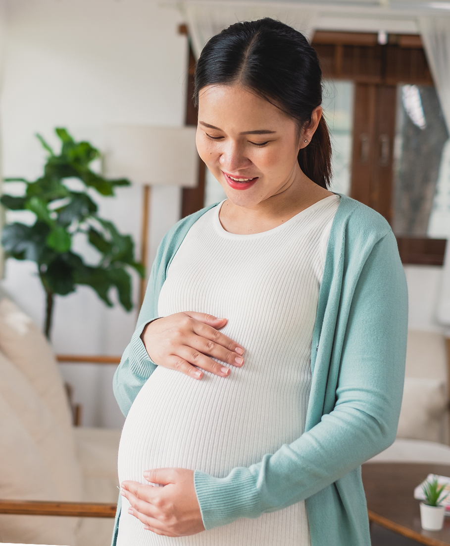 Pregnant woman in a light blue cardigan standing in a living room.