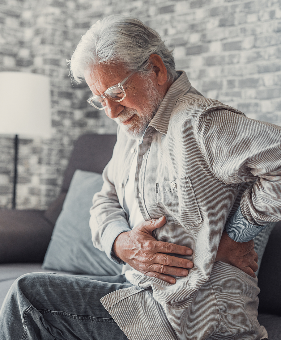 Senior man experiencing back pain in a living room setting.