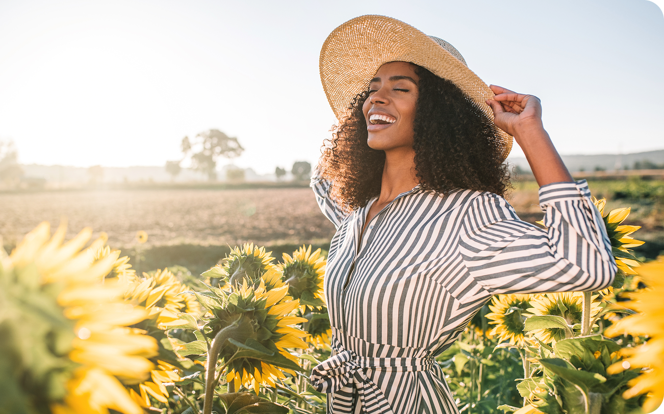 Woman in a striped shirt and sun hat standing in a sunflower field