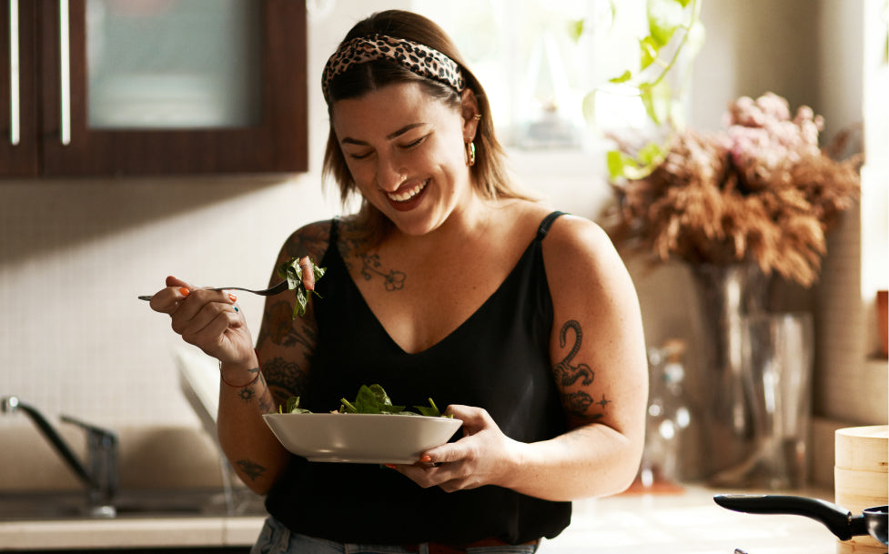 Woman holding a bowl of salad in a kitchen