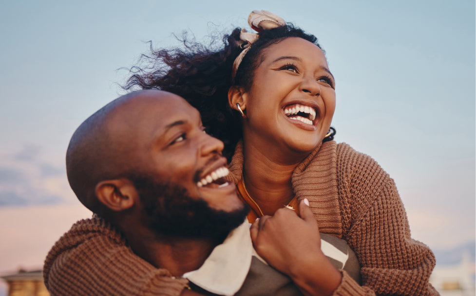 Couple laughing together outdoors with a clear sky background