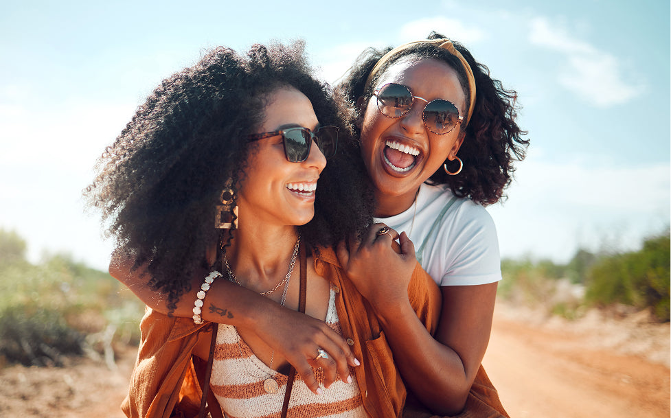 Two women laughing outdoors on a sunny day