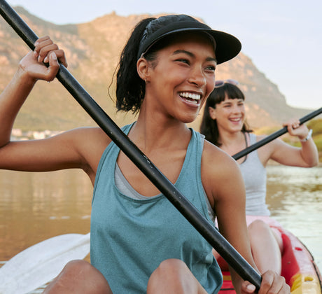 Two women paddling in a kayak on a lake with mountains in the background