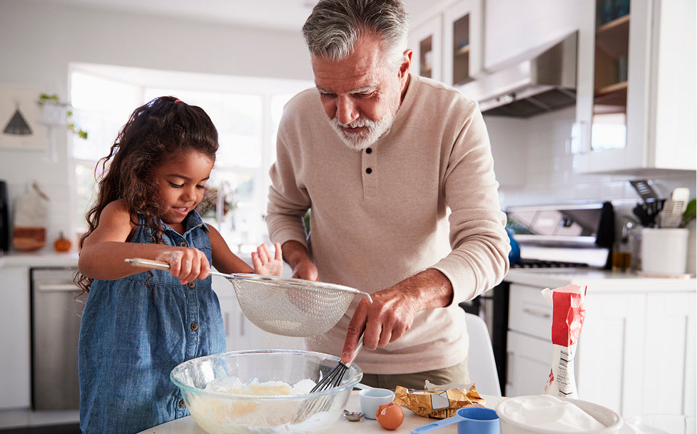 Man and young girl in a kitchen preparing food together.