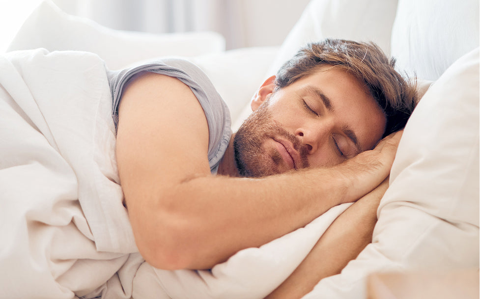 Man sleeping peacefully in bed with white bedding