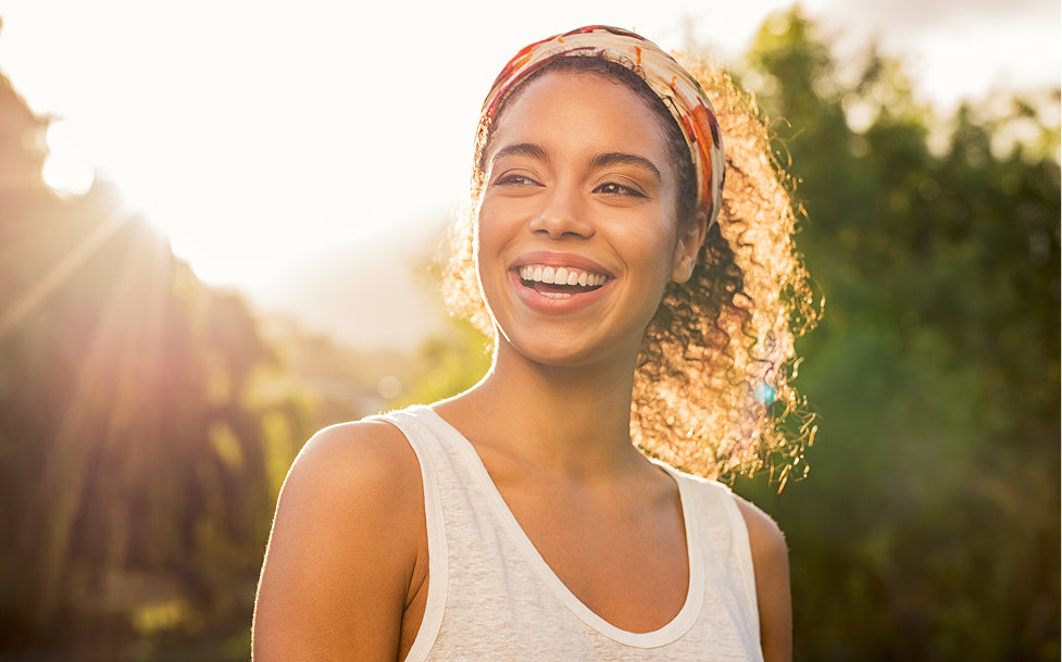 Woman smiling outdoors with a blurred natural background