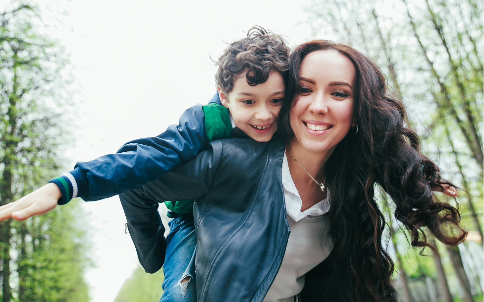 Woman giving a piggyback ride to a child in a park