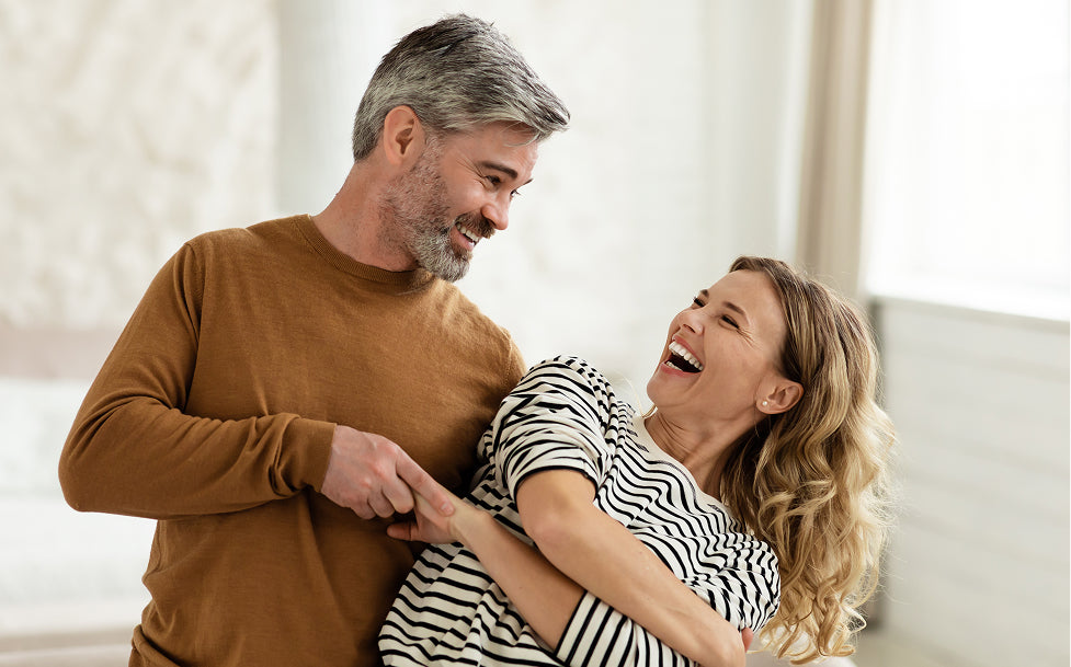 Man and woman laughing together in a bright room